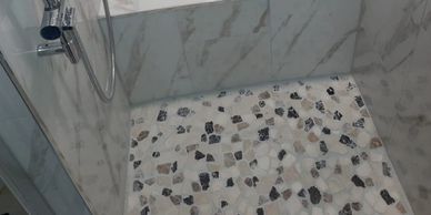 Shower area with patterned floor and marble walls.