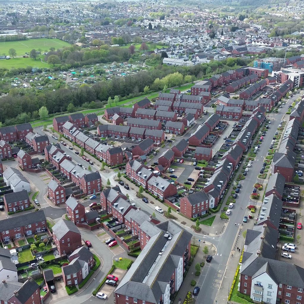 Aerial view of a suburban neighborhood with rows of red brick houses and greenery.