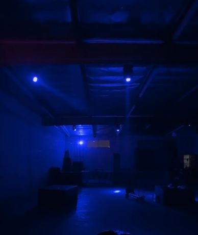 Dimly lit room bathed in blue light with industrial ceiling.