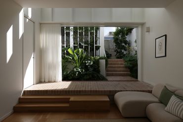 Minimalist living room with large window overlooking a green garden and stairs.