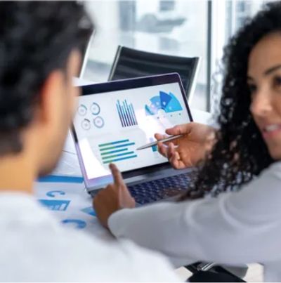 Two professionals analyzing data charts on a laptop screen.