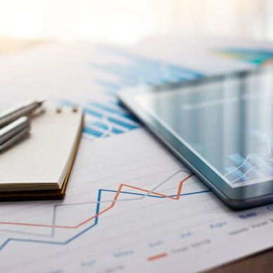 Tablet, notebook, and pen on financial charts.