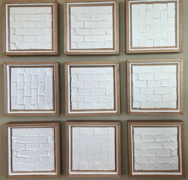 Nine small wooden square frames filled with tiny white brickwork arranged in a square