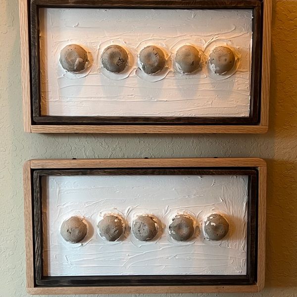 Two horizontal framed plaster rectangles with five brown clay dots arranged in a horizontal line