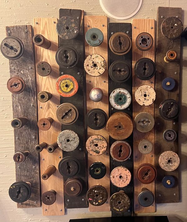 Mixed media piece of various wooden spools affixed to differently colored and shaped planks of wood