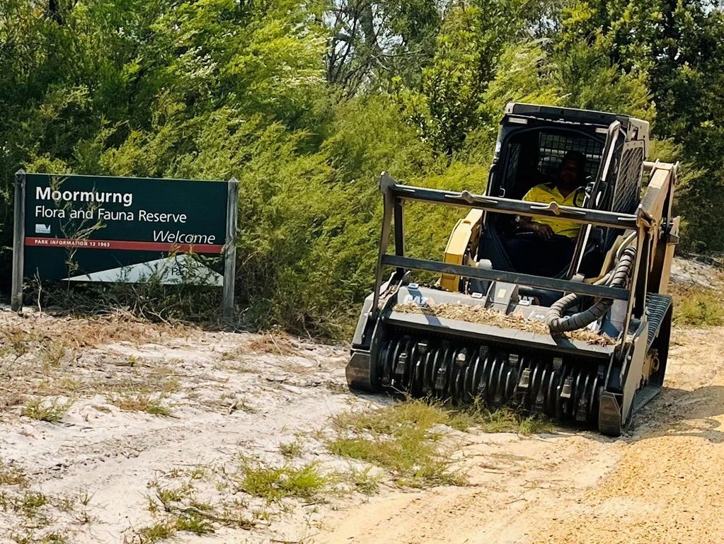 A worker operates heavy machinery near Moormurng Flora and Fauna Reserve sign.