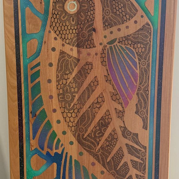 Intricate wooden artwork featuring a detailed fish design with colorful accents.