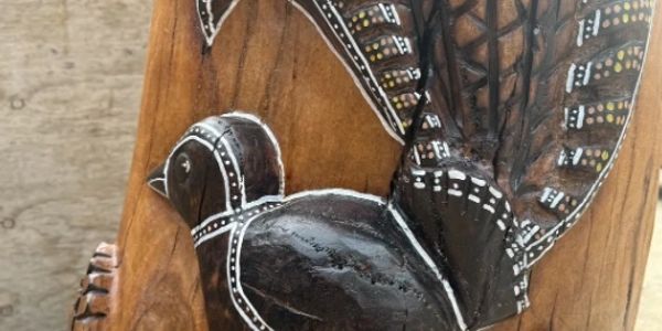 Detailed wooden carving of a bird with intricate patterns and natural wood finish.