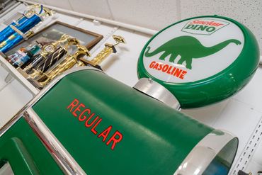 Vintage green Sinclair gas pump top with red "REGULAR" text and a circular Sinclair Dino logo globe.