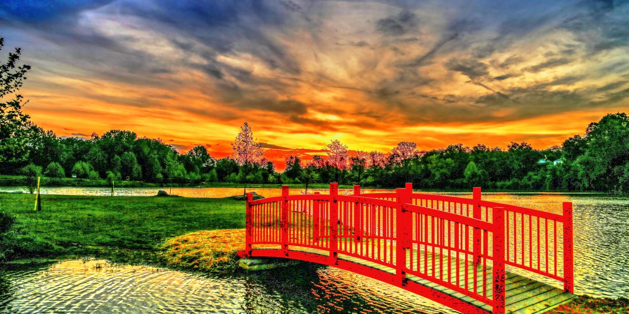 Red bridge over water at sunset.