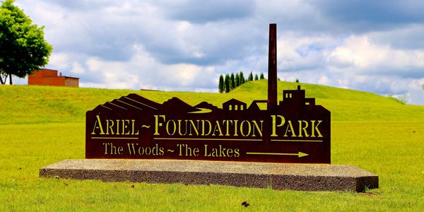 Sign for Ariel Foundation Park on a grassy field.