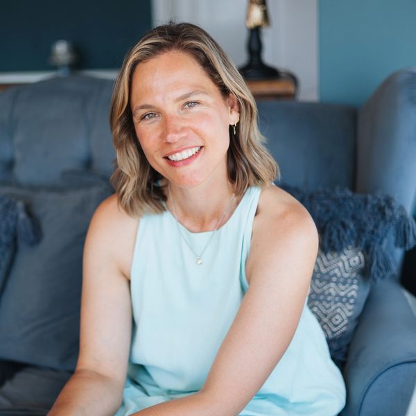 Smiling woman sitting on a blue couch with pillows. Angelic reiki practitioner in Leigh on Sea