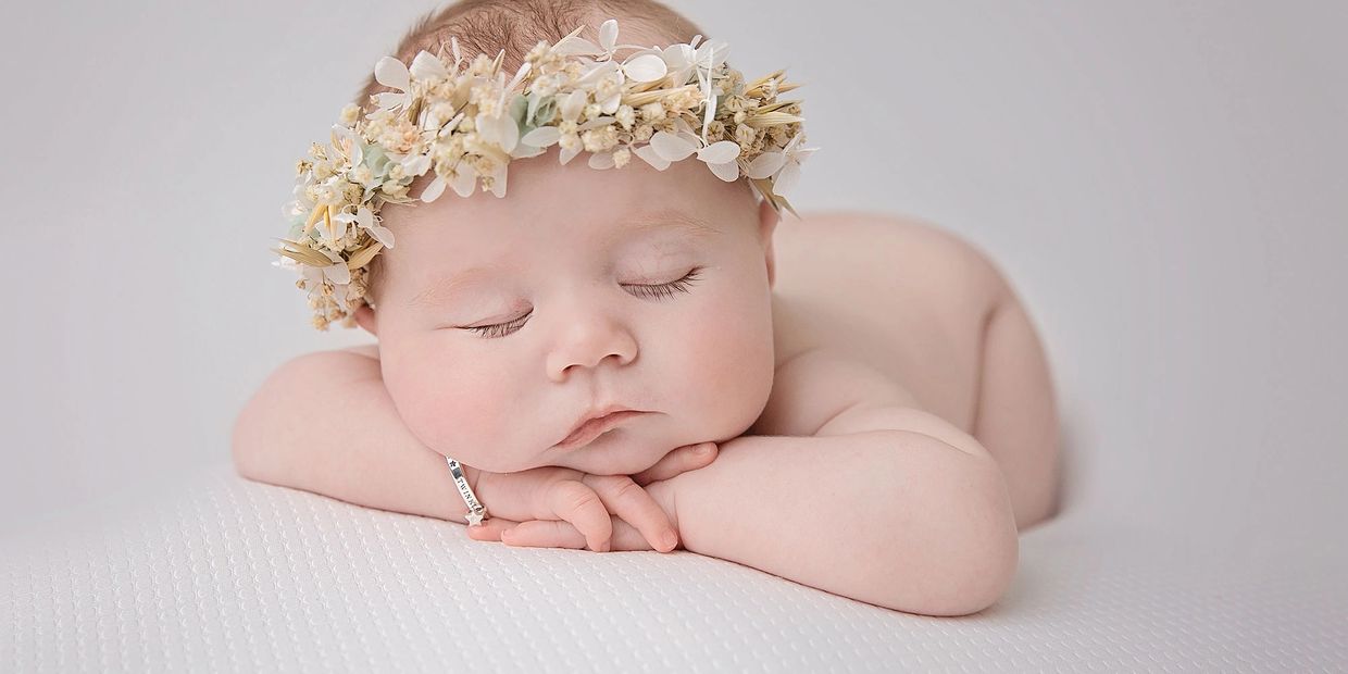 sleepy baby lying on tummy, resting on their arms with as floral halo headband
