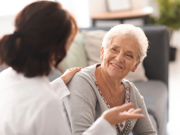 Young doctor visiting elderly woman at home