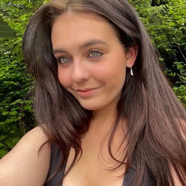 Young woman with long brown hair smiling outdoors.