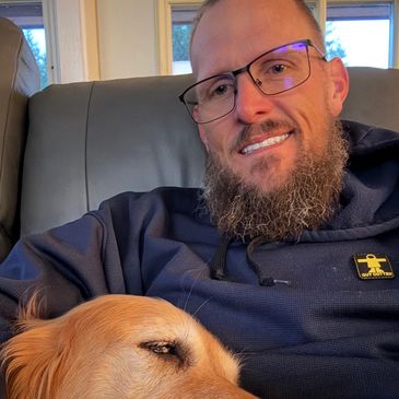 Man smiling with a dog on his lap.