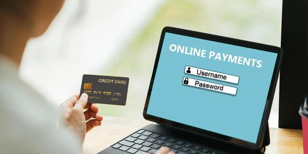 Individual holding a credit card and making an online payment.