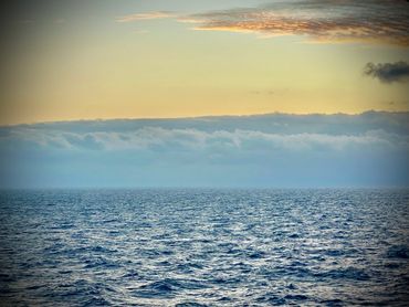 Calm ocean waters under a golden sky at sunset.