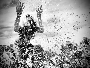 Black and white photo of a person playing in splashing water.
