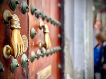 Close-up of ornate brass door knockers on a wooden door.