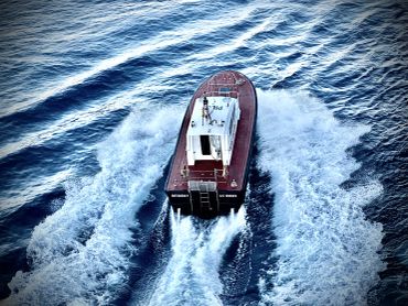 A small boat speeding through the water, leaving a trail of waves.