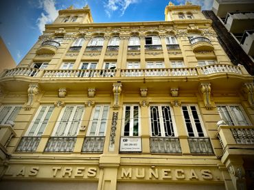 Historic yellow building with ornate balconies and windows under a blue sky.