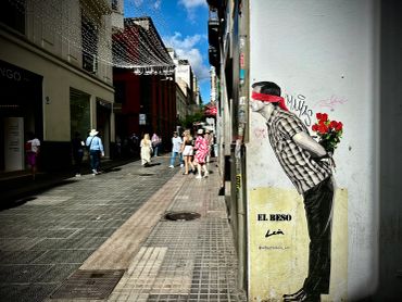 Street art shows a man blindfolded, holding flowers behind his back.