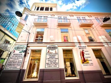 Facade of a vintage-style building with multiple signs and a clear sky above.