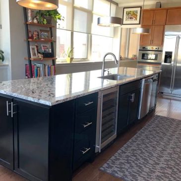 Modern kitchen island with granite countertop and appliances.
