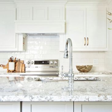 Bright modern kitchen with white cabinetry and marble countertops.