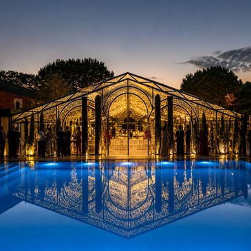 Elegant illuminated glass pavilion reflected in a tranquil pool at dusk.