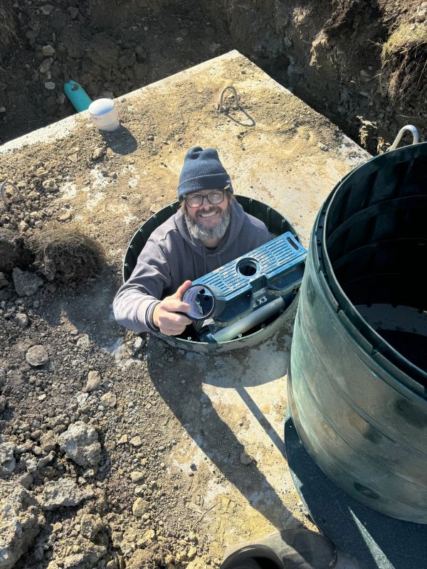 Man smiling while working in an underground utility hole.