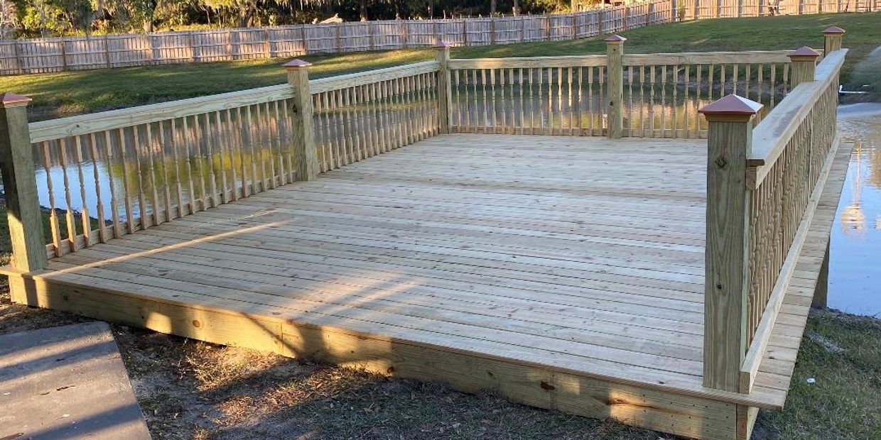 A wooden deck with railings Riverview, Deck Builder Odessa, Pergola Builder Tampa, Outdoor Kitchen Company