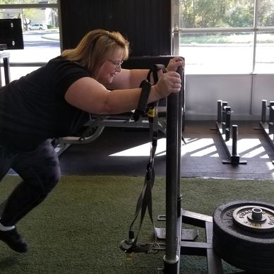 Client performing high intensity interval training sled push.