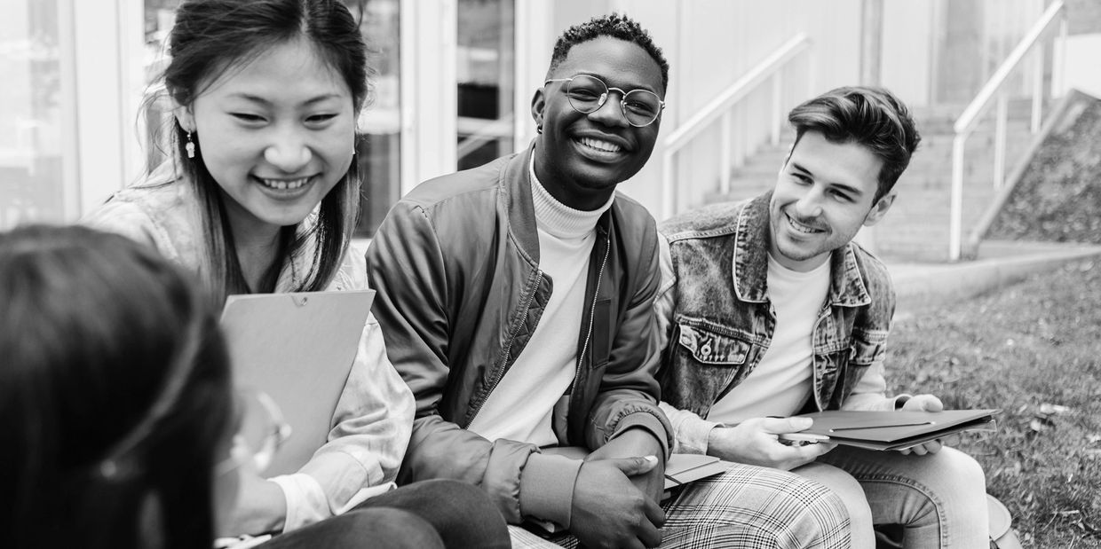 Group of diverse students chatting and smiling outdoors on campus.