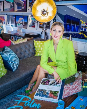 Woman in a green blazer sitting on a couch with a photo album.