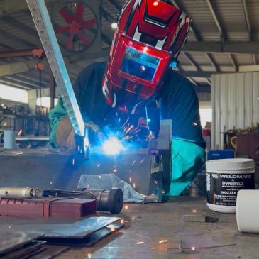 Welder working with sparks flying in a workshop.