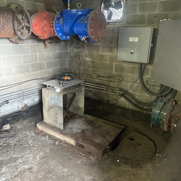 Old industrial equipment and pipes in a dim room.