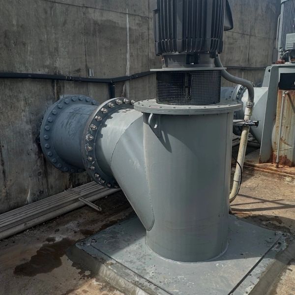 Industrial piping connected to machinery on a concrete floor.