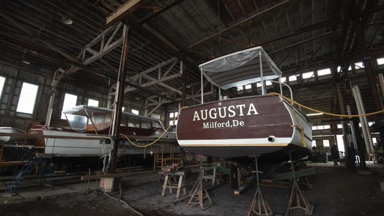 Boats stored and maintained in a large indoor dock or boatyard.