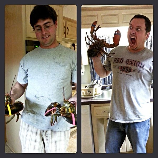 Men holding lobsters with playful expressions in a kitchen.
