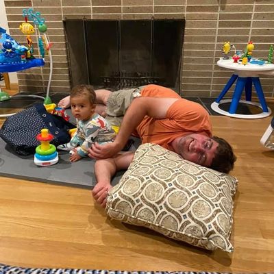 Man lying on floor with baby near fireplace.