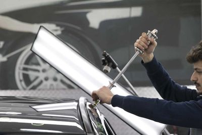 A man if fixing hail damage on a black car