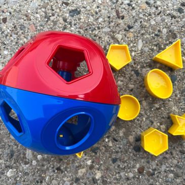 Children's plastic red and blue circular toy with yellow plastic shapes to insert in holes.