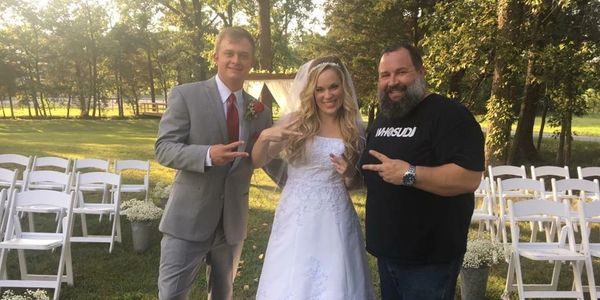 Bride and groom posing with DJ Peace of Peace Productions Mobile DJ Service at an outdoor wedding.