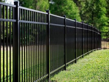 Black aluminum metal fence extending along a green lawn with a 3-year warranty badge.