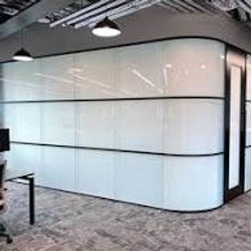Modern office space with glass walls and carpet flooring.