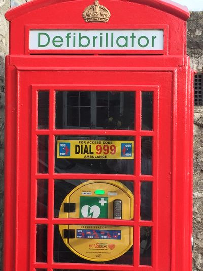 Image of a traditional red telephone kiosk that now has the sign "Defibrillator" and inside is a pub