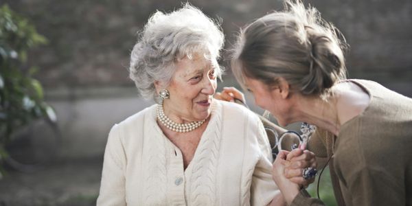 Older woman and younger woman sharing a joyful moment outdoors.