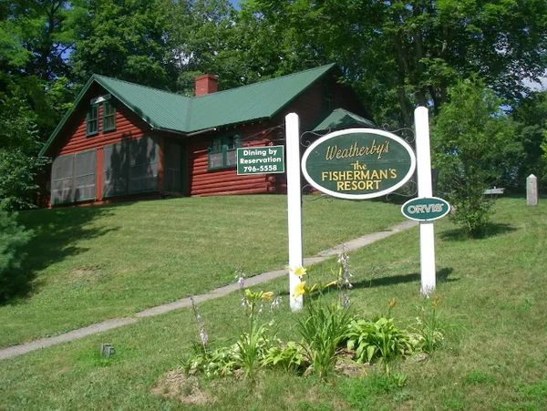 Log cabin at Weatherby's Fisherman's Resort with a green roof and signage.